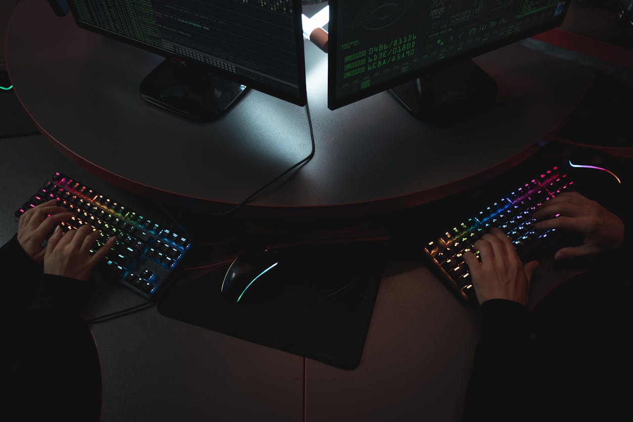 about-us Two people typing on RGB keyboards with code on screens, indicating a cybersecurity environment.